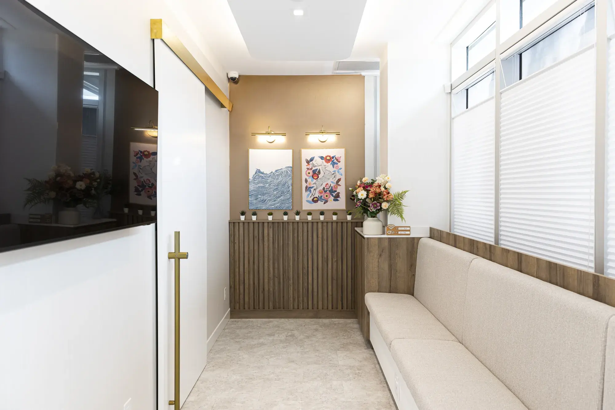 Waiting area with an upholstered bench, artwork, and flowers
